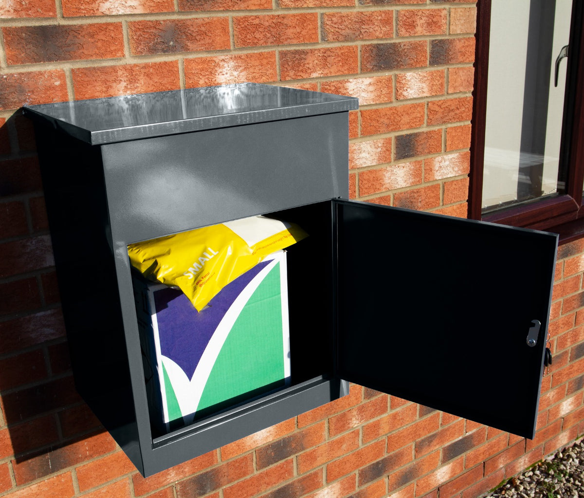 Grau lackierter Paketkasten mit schwarzer Tür, geöffnet, zeigt ein buntes Paket im Inneren, ideal für die sichere Zustellung von Paketen