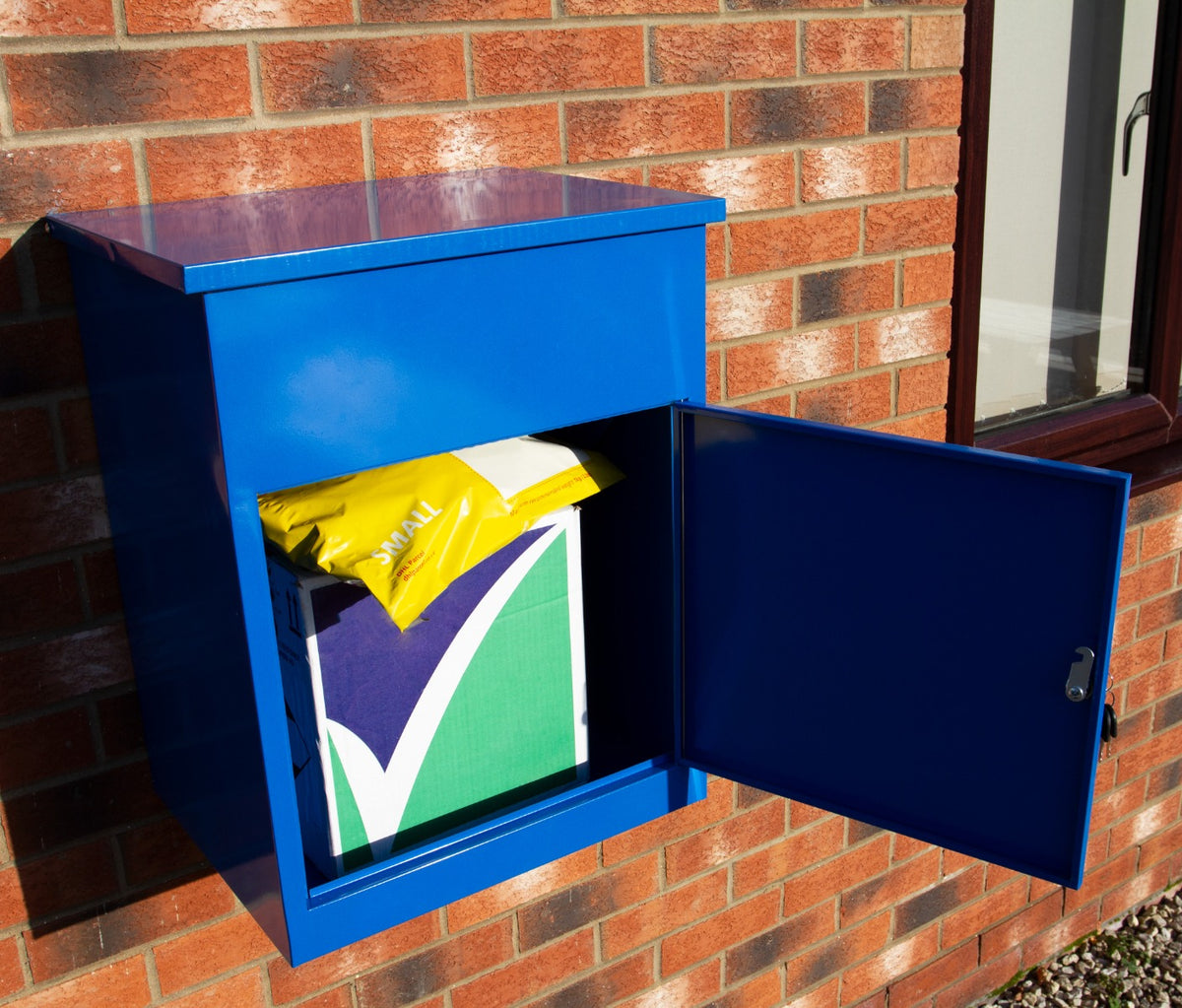 Blauer Paketkasten aus Metall mit glänzender Oberfläche, geöffnet, zeigt ein gelbes Paket und ein grünes, mit lila Design, auf einem Backstein-Hintergrund