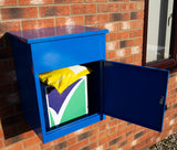 Blauer Paketkasten aus Metall mit glänzender Oberfläche, geöffnet, zeigt ein gelbes Paket und ein grünes, mit lila Design, auf einem Backstein-Hintergrund