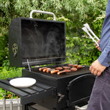 Schwarzer XL Holzkohlegrill Smoker mit rauchenden Würstchen und Steaks auf dem Rost, in einem grünen Garten mit einem Tisch und Grillzubehör
