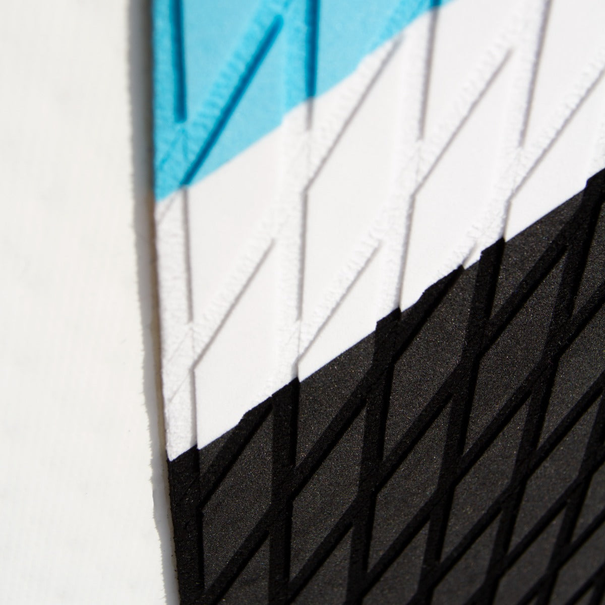 Detailansicht des blauen aufblasbaren Paddle Boards mit strukturiertem Griff, diagonalen Farbstreifen in Blau, Weiß und Schwarz, ideal für Wassersport
