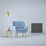 Anthrazitgrauer Paneelheizkörper mit schlanker, vertikaler Form, neben einem blauen Sessel und einem kleinen Tisch in modernem Raumdesign