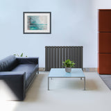 Anthrazitgrauer Paneelheizkörper mit vertikalen Lamellen, 600mm x 910mm, elegant in modernem Wohnraum, kombiniert mit minimalistischer Einrichtung und Pflanzen