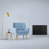 Schwarzer Paneelheizkörper mit vertikalen Lamellen, 600mm x 910mm, neben einem blauen Sessel und einer modernen Stehlampe in einem minimalistischen Raum