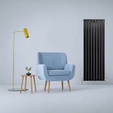 Schwarzer Paneelheizkörper mit vertikalen Lamellen, 1600mm x 560mm, elegant neben einem blauen Sessel und einer modernen Stehlampe platziert