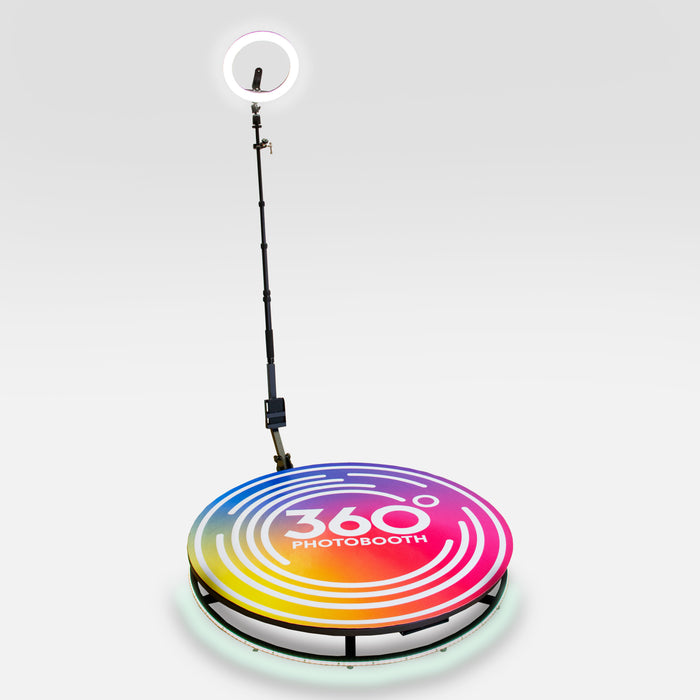 Bunte 360° Fotobox mit einem runden, leuchtenden Podest in Regenbogenfarben und einem Ringlicht, ideal für kreative Fotoshootings