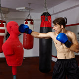 Ein muskulöser Mann in blauen Boxhandschuhen schlägt einen roten freistehenden Boxdummy in einem modernen Fitnessstudio mit Boxsäcken im Hintergrund