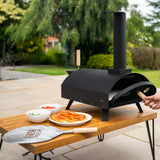 Klassischer Outdoor-Pizzaofen in mattschwarz, auf einem Holztisch, mit frischen Zutaten und einer Pizzaschaufel aus Edelstahl, ideal für Gartenpartys