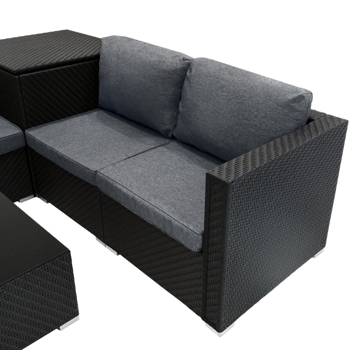 Schwarze Rattan-Sitzgarnitur mit grauen Kissen, bestehend aus einem L-förmigen Sofa und einem passenden Tisch, ideal für den Außenbereich