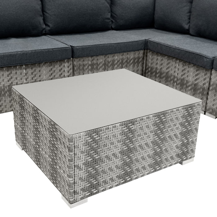 Quadratischer Couchtisch aus grauem Rattan mit glatter, heller Tischplatte, umgeben von einer gemütlichen, dunkelgrauen Sitzgruppe