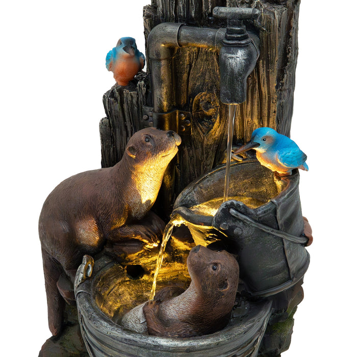 Eine dekorative Gartenbrunnen-Skulptur mit zwei Ottern und einem blauen Vogel, die an Eimern mit sprudelndem Wasser sitzen, aus wetterfestem Material gefertigt