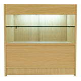 Verkaufstheke aus hellem Ahornholz mit gläsernem Regal, beleuchtet von oben, ideal für die Präsentation von Produkten in Geschäften