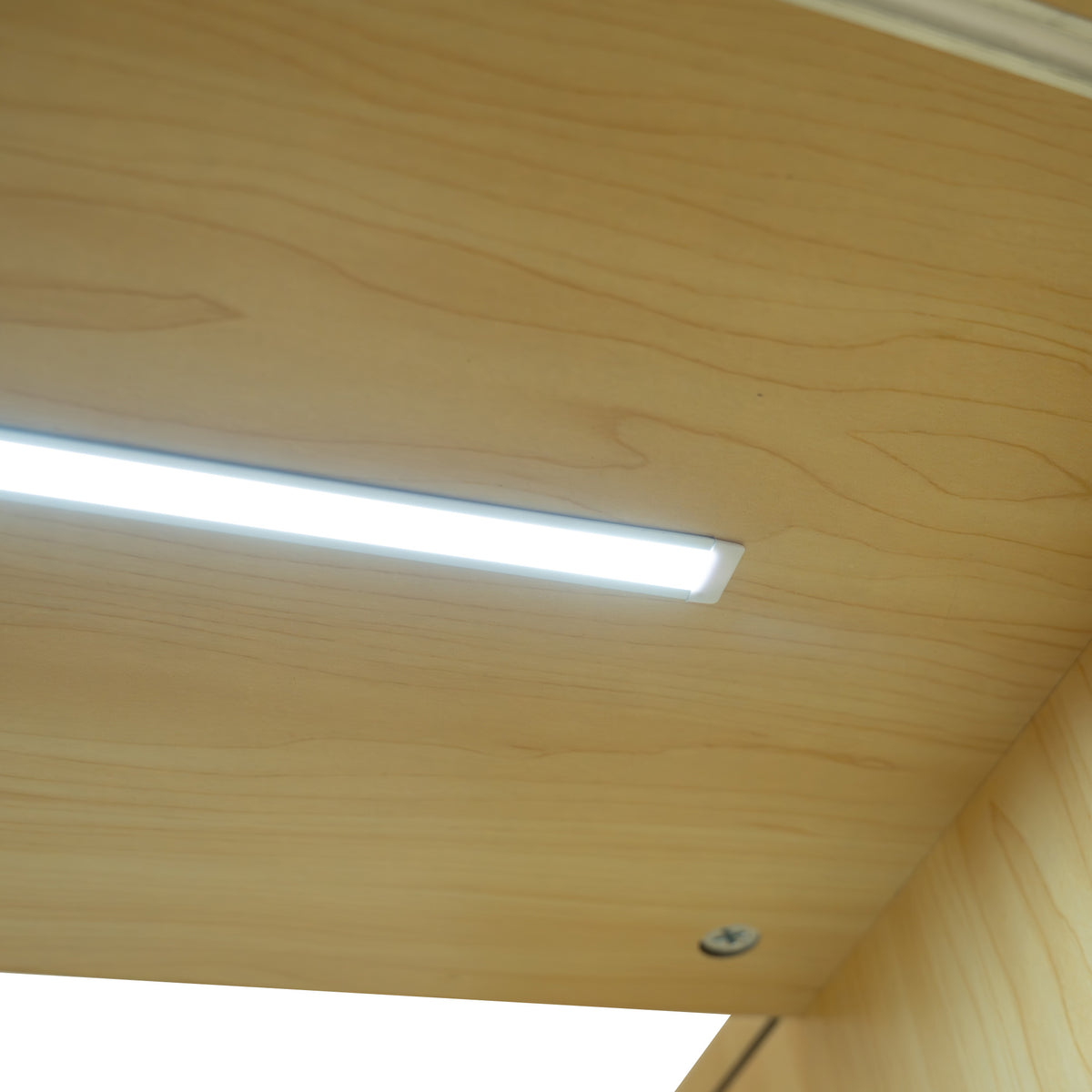 Helle LED-Beleuchtung auf einer glatten, hellen Ahorn-Oberfläche des Calliope Verkaufstheken-Sets, ideal für moderne Verkaufsräume