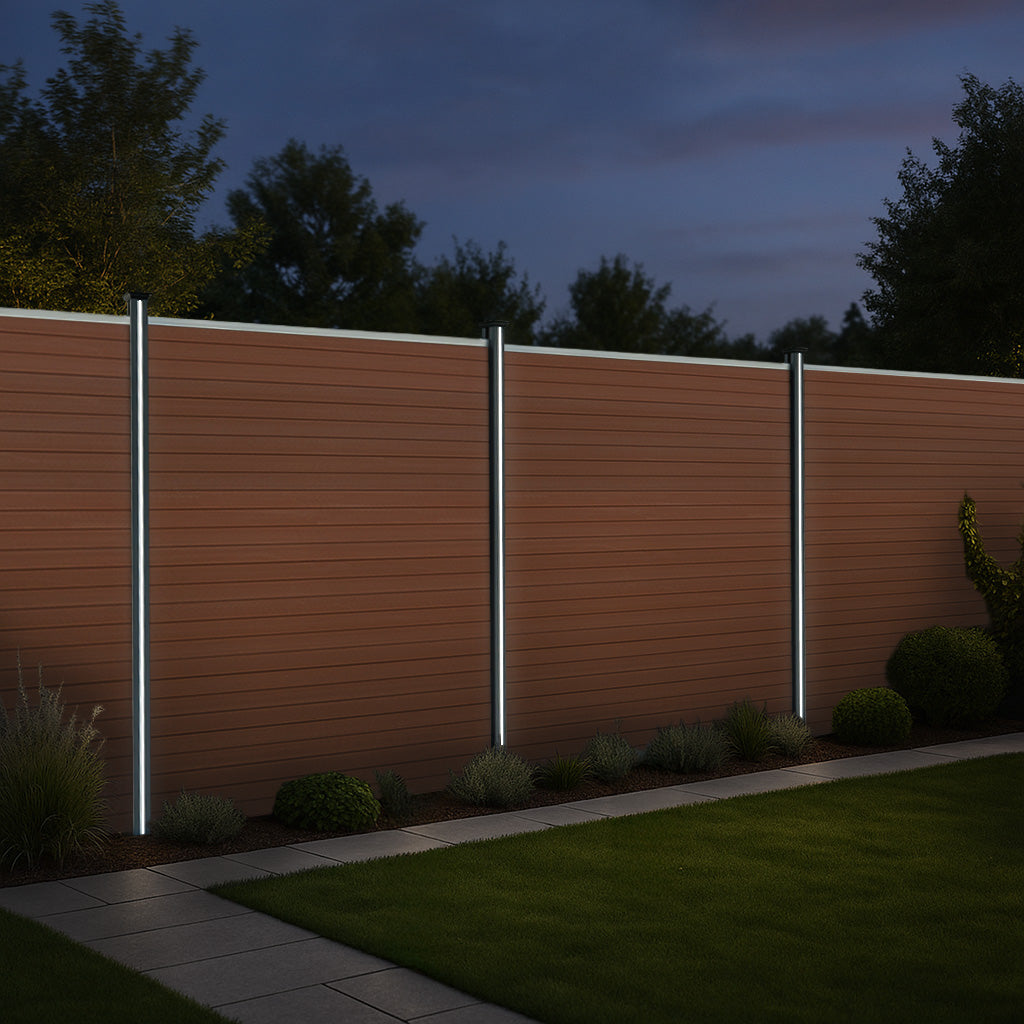 Brauner WPC Sichtschutzzaun mit LED Zaunpfosten, stilvoll beleuchtet, umgeben von grünem Rasen und Pflanzen, ideal für Garten- und Terrassengestaltung