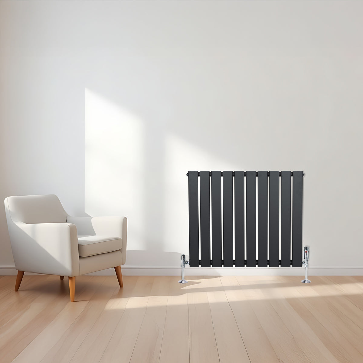 Flachheizkörper in Anthrazitgrau, 600mm x 700mm, mit vertikalen Lamellen und glänzenden Ventilen, steht neben einem modernen weißen Sessel auf hellem Holzfußboden