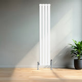 Flachheizkörper in Weiß, 1600mm x 280mm, mit glatten, vertikalen Lamellen und glänzenden Ventilen, vor einer hellen Wand und einem Pflanzenarrangement