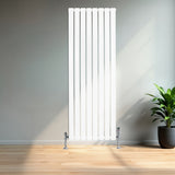 Flachheizkörper in Weiß, 1600mm x 560mm, mit vertikalen Lamellen und glänzenden Ventilen, steht elegant in einem modernen Raum mit Holzfußboden und Pflanze