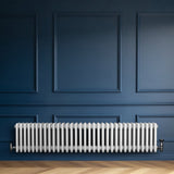 Röhrenheizkörper mit vier Säulen in Weiß, elegant und modern, montiert an einer blauen Wand, ergänzt durch einen hellen Holzboden