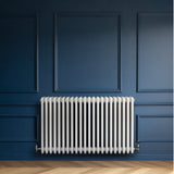 Röhrenheizkörper mit vier Säulen in elegantem Weiß, 600mm x 1010mm, an einer blauen Wand, verleiht modernen Räumen Wärme und Stil
