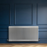 Röhrenheizkörper mit vier Säulen in Weiß, 600mm x 1190mm, vor einer blauen Wand, mit glatter, glänzender Oberfläche und eleganter, moderner Form