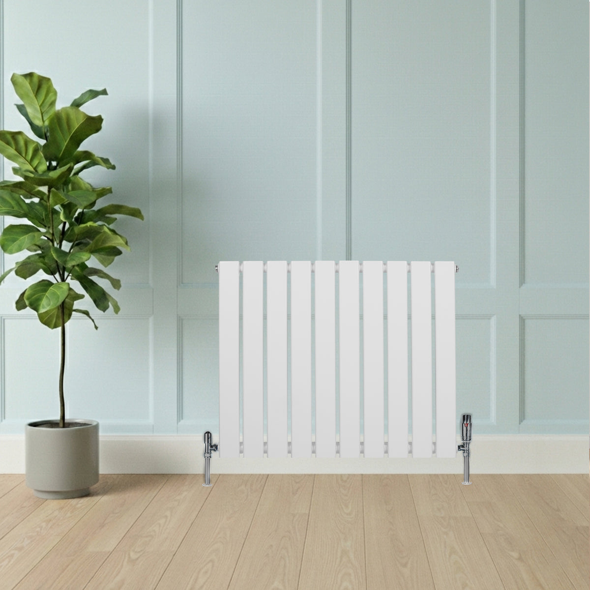 Flachheizkörper in Weiß, 600mm x 700mm, mit schlanken vertikalen Lamellen und verchromten Ventilen, vor einer hellblauen Wand und Holzfußboden