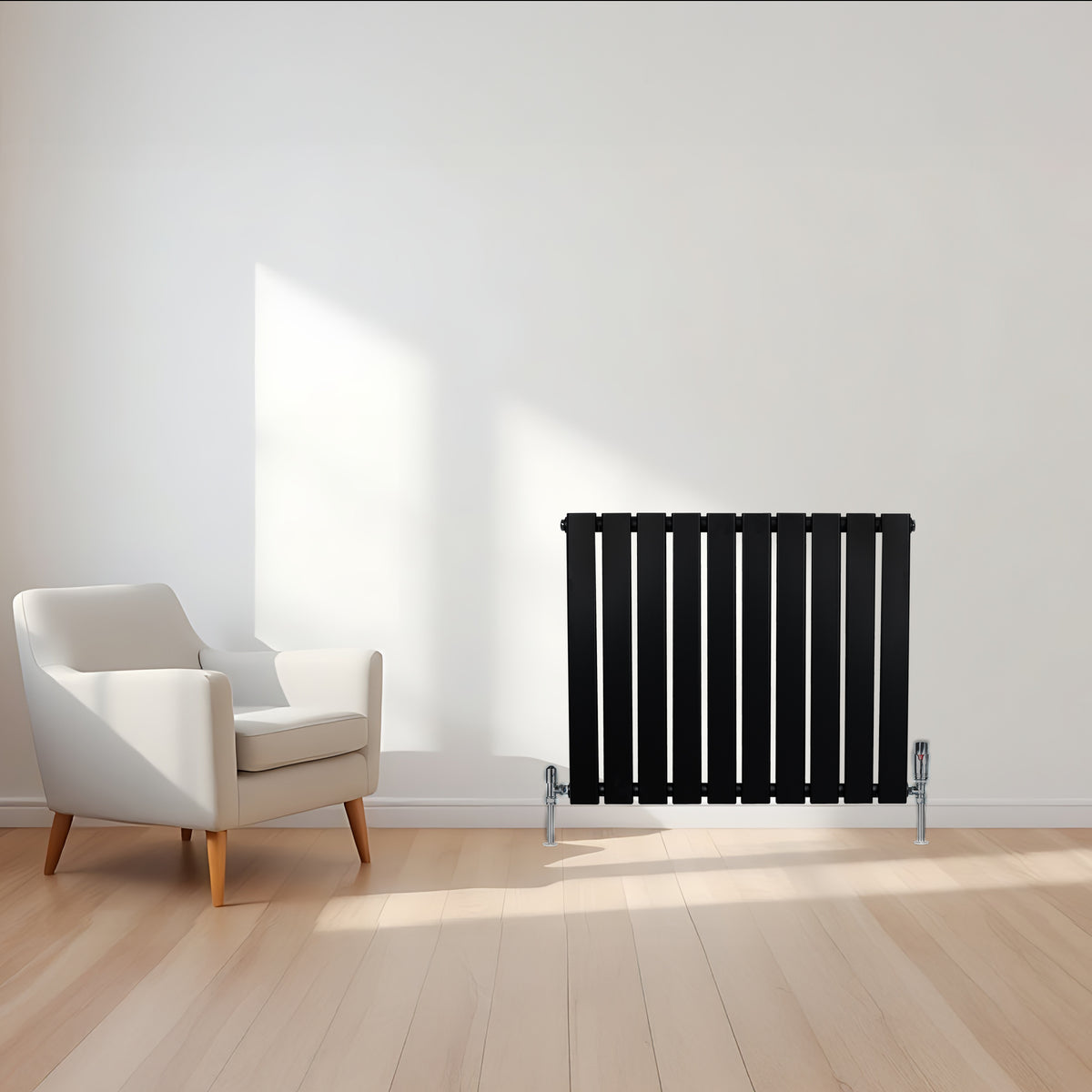 Schwarzer Flachheizkörper mit vertikalen Lamellen, 600mm x 700mm, vor einer hellen Wand und einem modernen weißen Sessel auf Holzfußboden