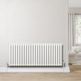 Gliederheizkörper in Weiß, 600mm x 1440mm, mit vertikalen Lamellen und glänzenden Metallfüßen, vor einer hellen Wand und einem gemütlichen Wohnraum