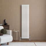Hochformatiger, weißer Gliederheizkörper mit sechs vertikalen Elementen, elegant an einer beige Wand montiert, umgeben von modernem Wohnambiente