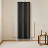 Schwarzer Gliederheizkörper mit vertikalen Lamellen, 1800mm x 600mm, elegant in modernem Raum, Holzfußboden und stilvollem Tisch im Vordergrund