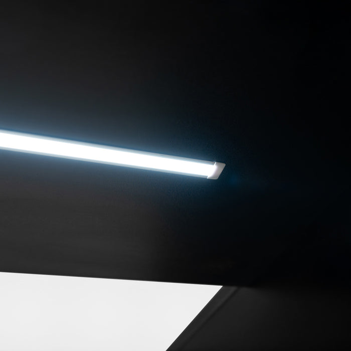 Helle LED-Leuchte mit schlankem, modernem Design an einer dunklen Decke, die einen klaren Lichtstrahl auf einen weißen Bereich wirft