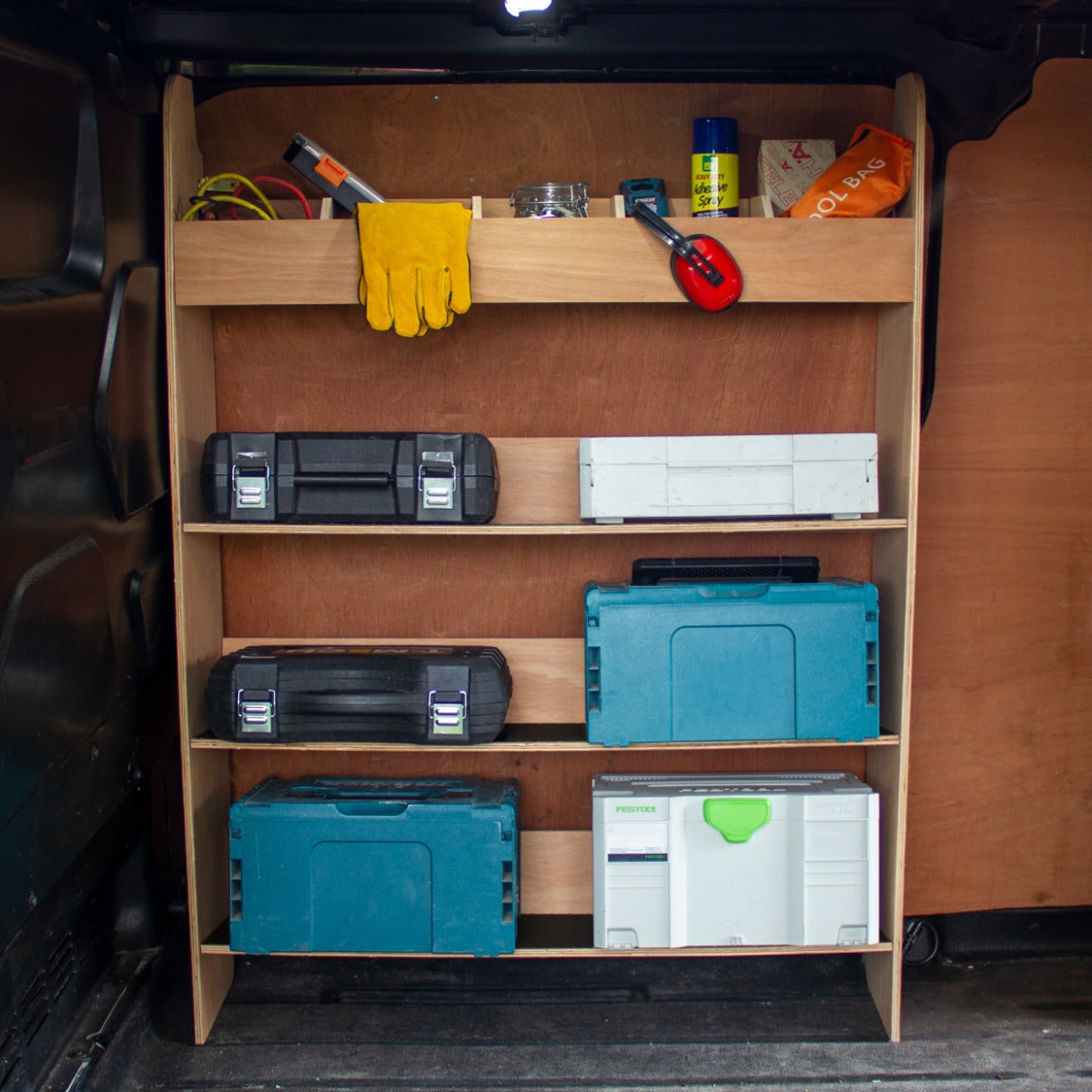 Holzregal mit Werkzeugkasten in einem Ford Transit Custom, ausgestattet mit blauen und grauen Kisten, Handschuhen und Werkzeugen auf einer stabilen Ablage