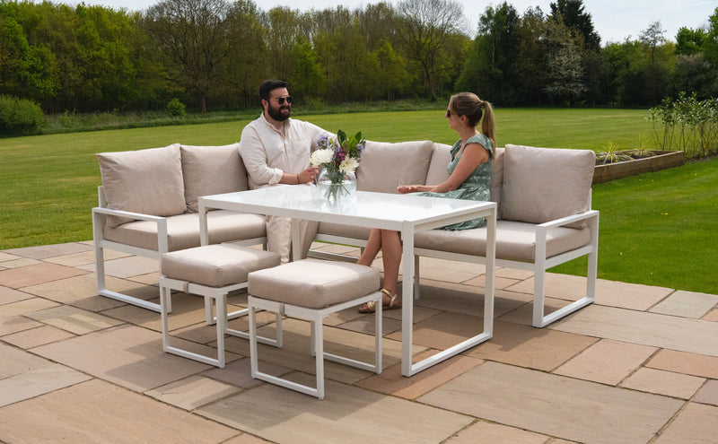Moderne Gartenmöbel aus weißem Aluminium mit beigen Polstern, Tisch und Stühlen, ideal für entspannte Stunden im Freien mit Freunden oder Familie