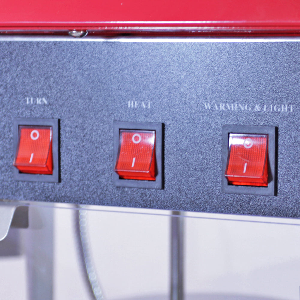 Drei rote Schalter auf einer schwarzen Oberfläche der KuKoo Retro Popcornmaschine, beschriftet mit TURN, HEAT und WARMING & LIGHT, glänzende Textur