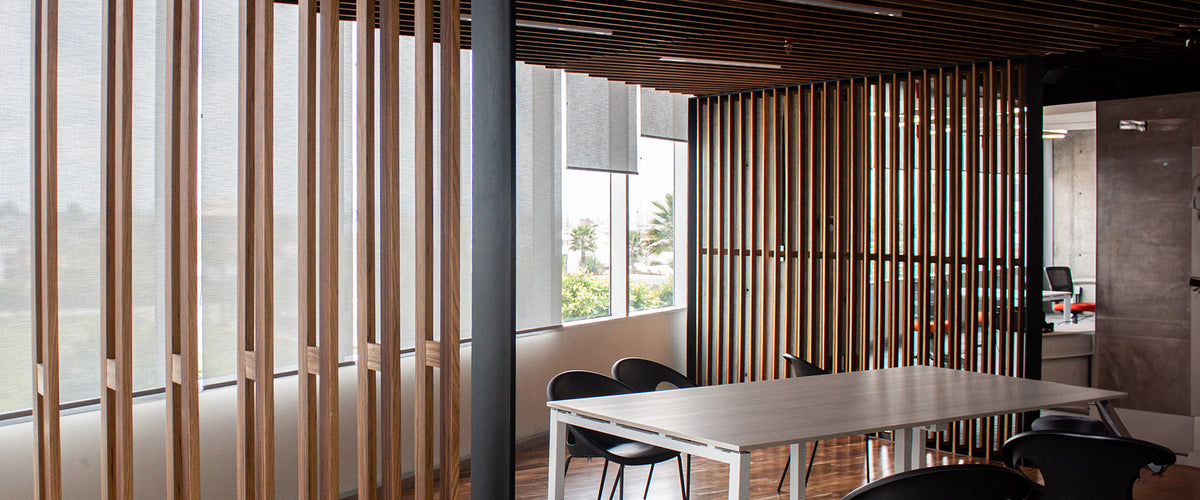 Heller, moderner Büroraum mit Holzlamellen, großen Fenstern und einem minimalistischen Tisch, umgeben von schwarzen Stühlen und natürlichem Licht