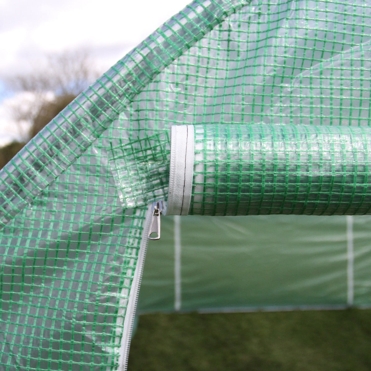 Transparente grüne Polytunnelfolie mit Netzstruktur, die einen Reißverschluss zeigt, ideal für den Schutz von Pflanzen im Garten