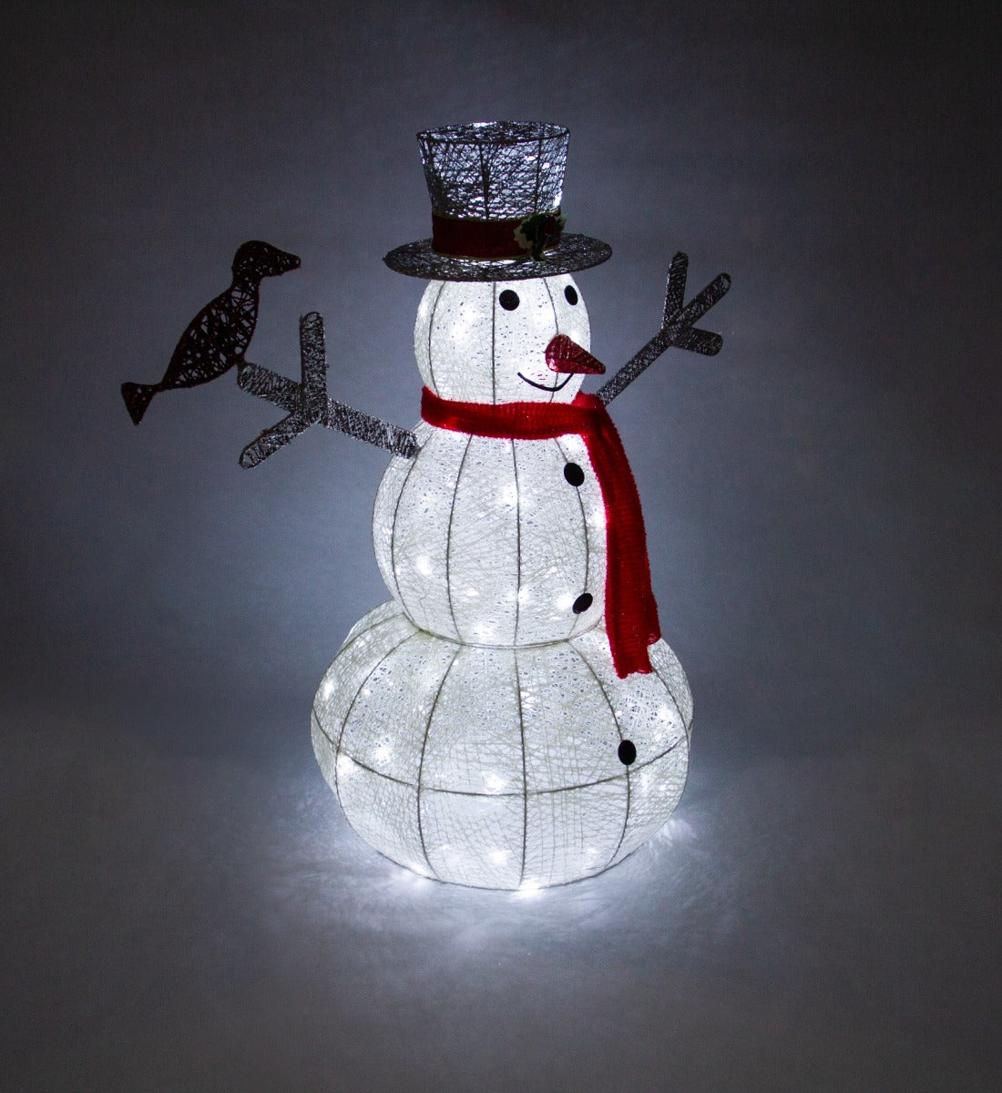 Beleuchteter Schneemann aus weißem Drahtgeflecht mit rotem Schal, schwarzem Hut und einem kleinen Vogel, der auf einem Arm sitzt
