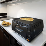 Schwarzer Mini Tandoor Ofen auf einer modernen Küchenarbeitsplatte, mit frisch gebackenem Naanbrot darauf und einem Teller daneben