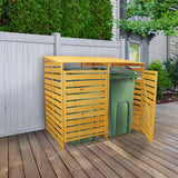Mülltonnenverkleidung aus hellem Holz mit horizontalen Lamellen, schützt zwei grüne Mülltonnen, steht auf einem Holzdeck, umgeben von einem Gartenzaun